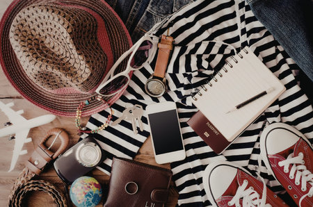 A collection of travel essentials including a hat, sunglasses, phone, passport, notebook, and shoes...