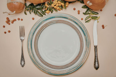 A table setting with a plate, fork, knife, and decorative elements like fruits and leaves.