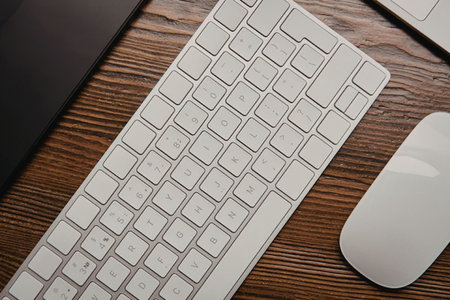 A white computer keyboard and mouse on a wooden desk