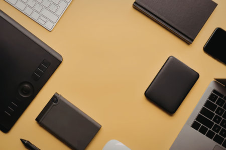 A collection of electronic devices and gadgets on a yellow desk