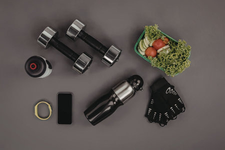 A selection of fitness equipment and healthy food on a gray background