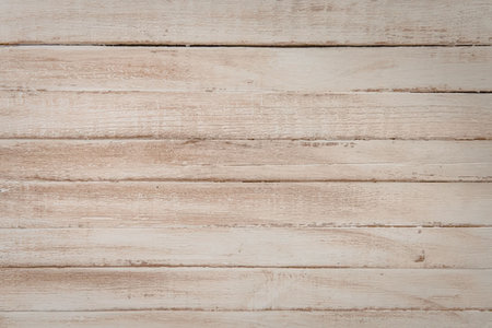 A close-up of light colored wooden planks with visible grain and texture, arranged horizontally.