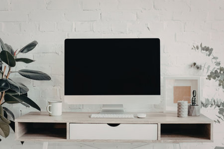 A modern home office setup featuring a large screen television on a wooden entertainment center with...
