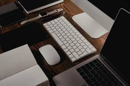A modern workspace setup featuring a laptop, keyboard, mouse, and other office accessories on a...