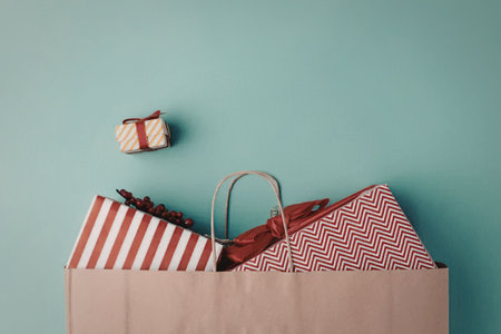 A brown paper shopping bag with red and white gift boxes and a small present on a light blue...