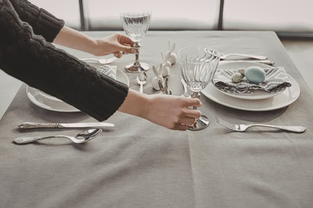 a person setting a formal table with plates, glasses, and silverware