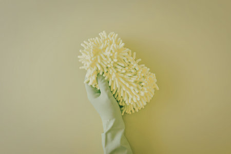 A hand wearing a green glove holding a green duster