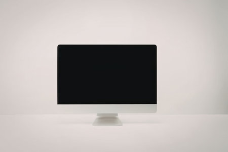 A computer monitor with a black screen sits on a white surface against a white wall.の写真素材