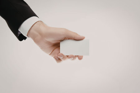 A hand in a business suit holding a blank white card