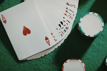 A fanned hand of poker cards with chips on a green felt table.