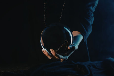 A person is holding a crystal ball in their hand, with a dark background and blue lighting.