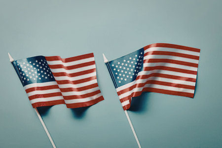 Two small American flags waving on a light blue background