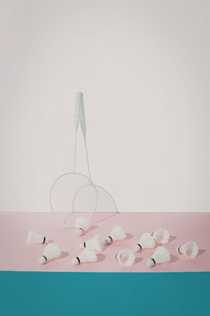 A badminton racket and shuttlecocks on a pink and blue surface