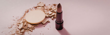 A broken compact powder and a lipstick on a pink surfaceの写真素材