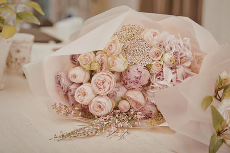 A stunning bouquet of pink roses and flowers wrapped in pink paper on a tableの写真素材