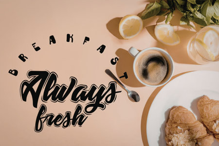 A breakfast setup with croissants, coffee, and lemons on a peach backgroundの写真素材