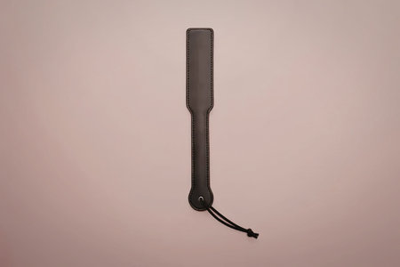 A black leather strap is displayed on a pink background.