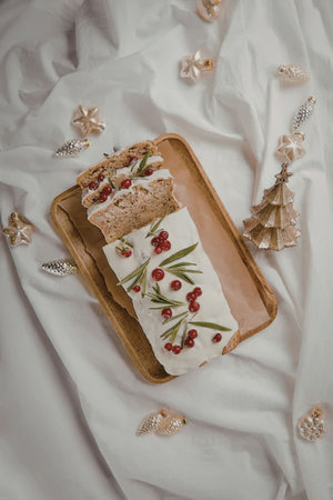 A Christmas log cake with white frosting and red berries on a wooden tray