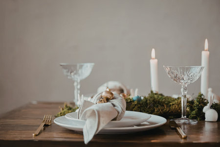 A beautifully set table with white plates, glasses, and candles for a festive Christmas dinner.