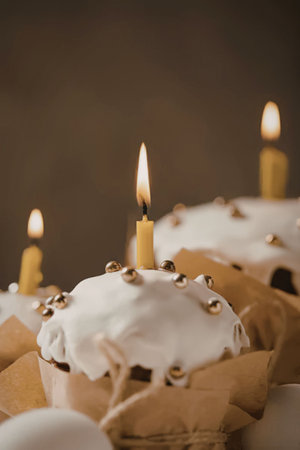 Easter bread with white icing and lit candles on top, decorated with golden beadsの写真素材