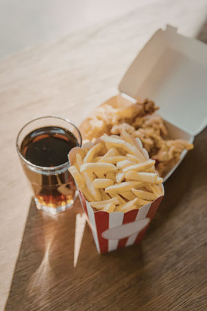 A container of fries and a drink on a table