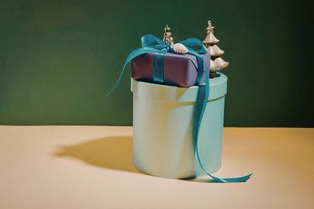 A gift box with a purple gift and blue ribbon, accompanied by small Christmas trees on top.