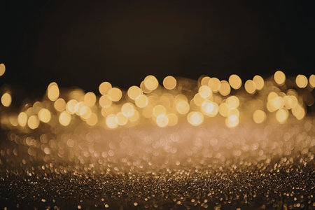 A blurry image of golden lights on a dark background with sparkling particles