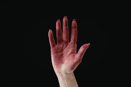 A hand with pink paint on fingers against a black backgroundの写真素材