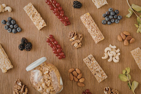 An assortment of healthy snacks including granola bars, nuts, and fresh fruits on a wooden surface.