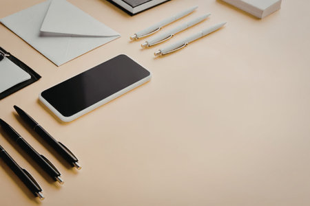 A neatly arranged office desk with a mobile phone, pens, pencils, and stationery on a yellow...
