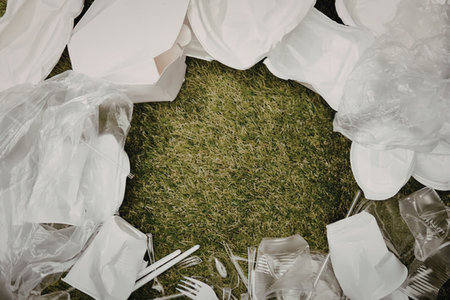 An aerial view of a pile of plastic waste including bags and bottles on a patch of green grass