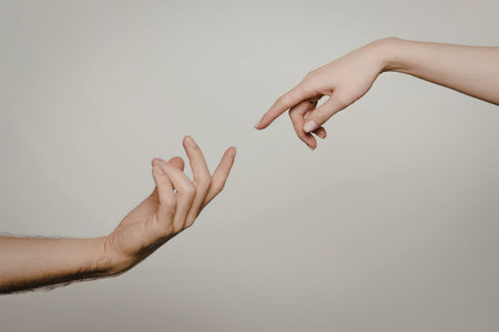 Two hands reaching out to touch each other, one with fingers extended and the other with index...