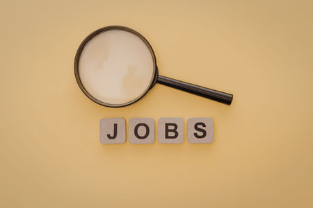 A magnifying glass over the word 'JOBS' on a yellow background, symbolizing the search for employment.の写真素材