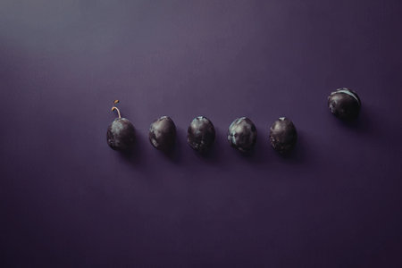 An image of seven small, dark, oval-shaped objects arranged in a line on a purple background.の写真素材