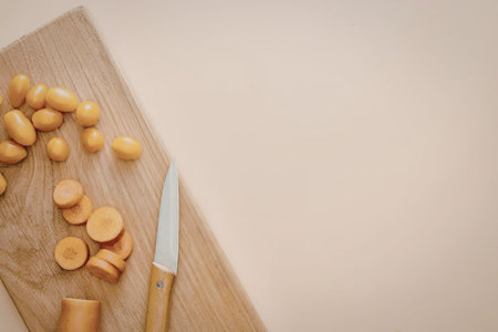 A wooden cutting board with sliced and whole vegetables and a knife