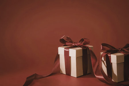 Two gift boxes with red ribbons on a red background, likely for a special occasion or holidayの写真素材