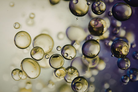 An image of numerous bubbles of various sizes floating against a blurred purple and green...