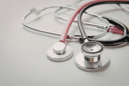 A stethoscope with a pink tube and silver metal parts lies on a white surface.