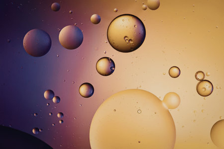 An image of various sized oil droplets floating in a vibrant purple and orange gradient backgroundの写真素材