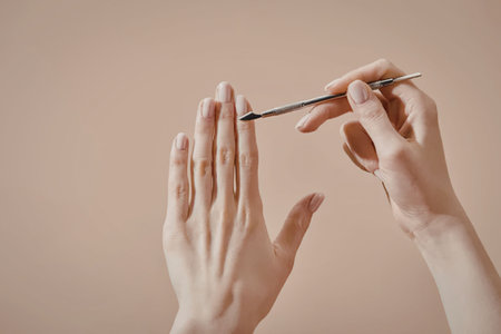 A close-up shot of a person's hands, one holding a nail file and the other having their nails filed.
