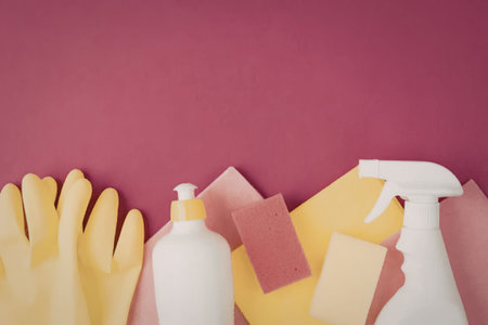 Brightly colored cleaning supplies including rubber gloves, sponges, and white spray bottles are...