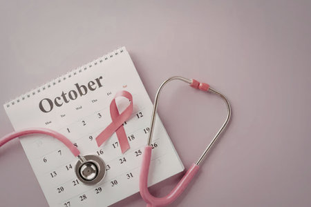Breast cancer awareness symbolized by pink ribbon on October calendar page with stethoscope on pink...
