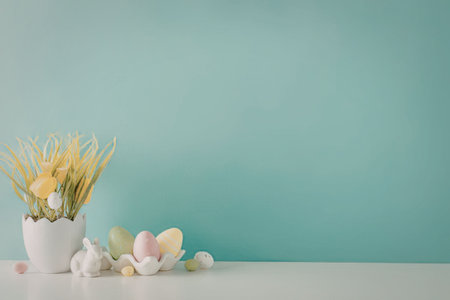 Colorful Easter eggs and grass in a white pot on a table against a soft pastel blue background creating a serene and festive atmosphere for the holiday season.の写真素材