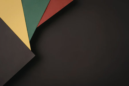 Colorful paper fragments in red, green, and yellow are arranged on a dark background providing a visually appealing contrast and ample copy space.の写真素材