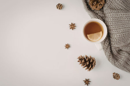 Warming tea with lemon rests beside a chunky gray knit scarf and scattered star anise spices...