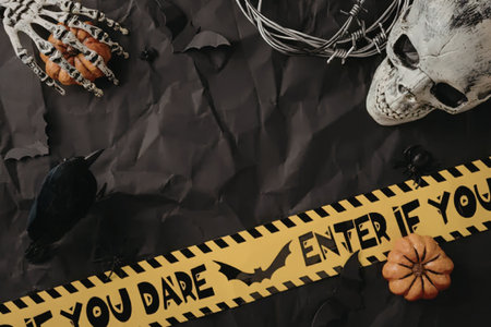 Eerie Halloween flat lay composition features a menacing skull, skeletal hand, pumpkin, dark raven,...