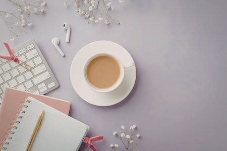 Coffee cup and notebooks on a lavender purple background with a keyboard and flowers creating a...