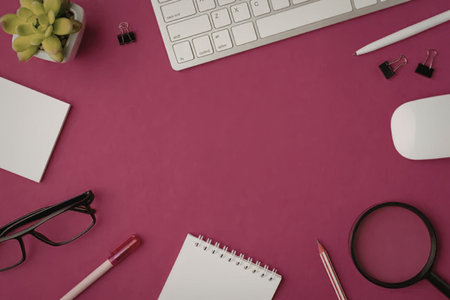 Office desk with keyboard, mouse, notebook, pen, pencil, glasses, and magnifying glass on a vibrant...