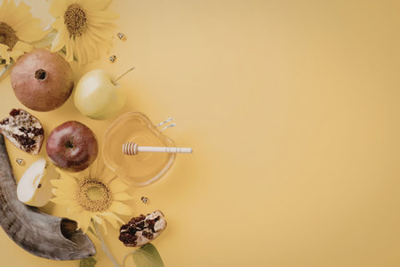 Rosh Hashanah celebration with apples, pomegranate, honey, and sunflowers on a yellow background, symbolizing a sweet new year and traditional Jewish holiday customs.の写真素材