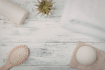 Spa essentials including a body brush, soap, and towels neatly arranged on a rustic white wooden...